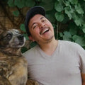 Man laughing with a dog in a natural setting